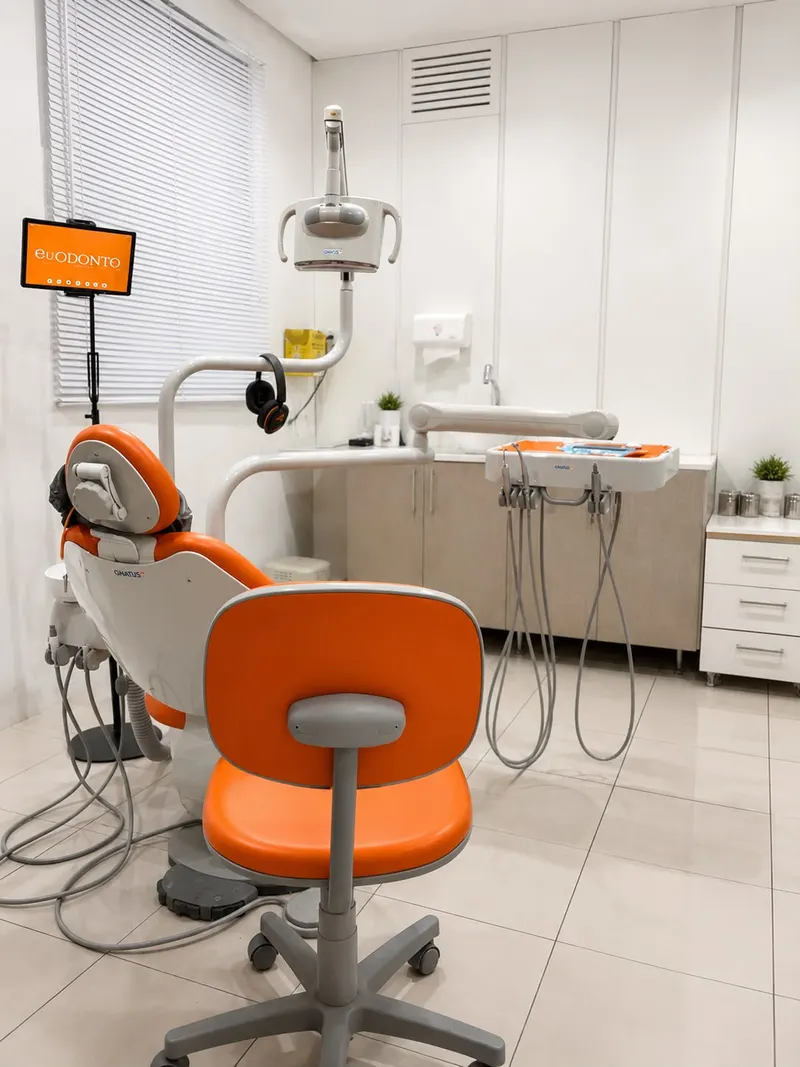 Sala de atendimento da EuOdonto com a cadeira odontológica laranja, na cor da marca