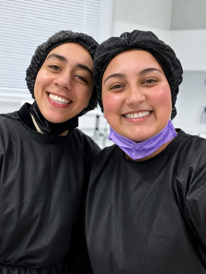 As doutoras da EuOdonto paramentadas para atendimento, sorrindo lado a lado na sala clínica